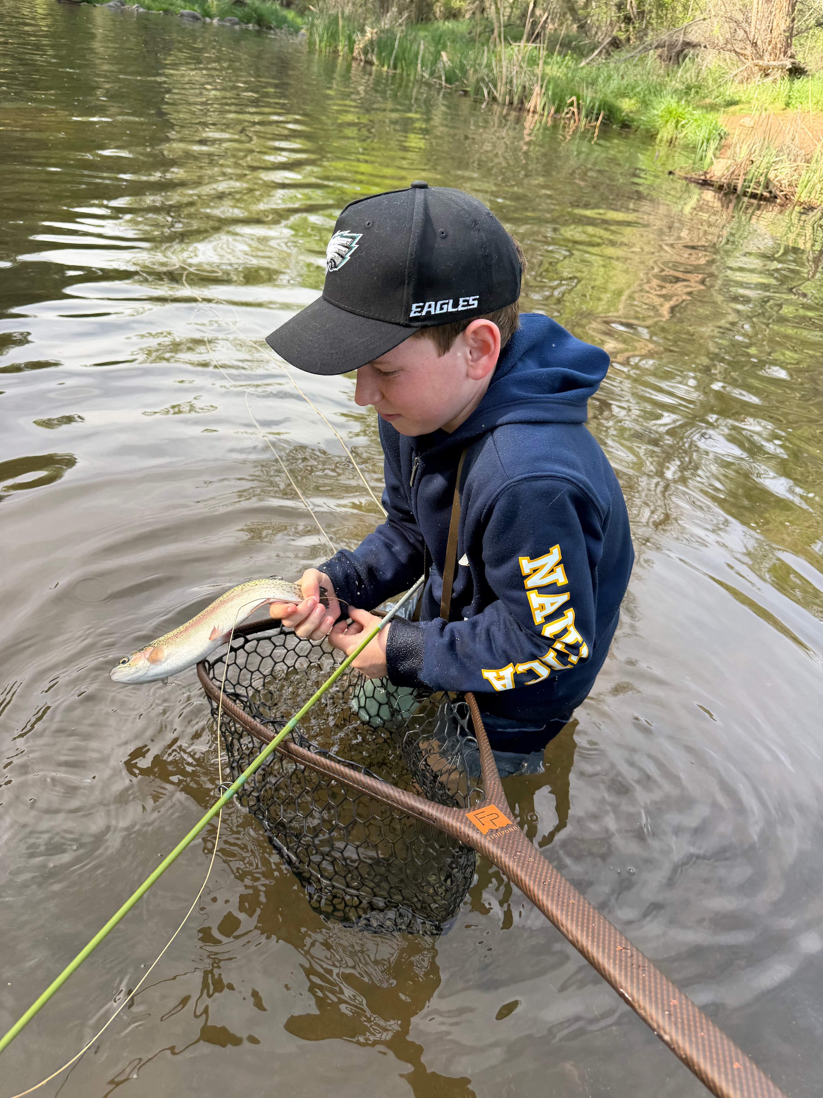 Young angler netting a trout streamside